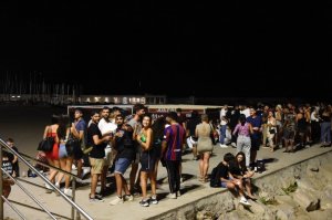 Young people gathering on the breakwater at Fragata beach in Sitges.