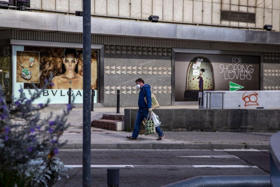 A man walking in Barcelona with shopping bags from El Corte Ingles